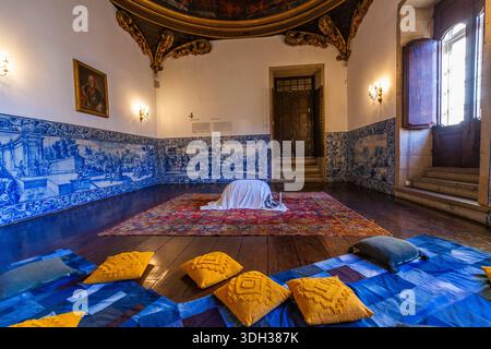 Biscainhos museum. Braga. An opulent room features walls adorned with blue and white ceramic tile murals, a richly patterned rug, and ornate golden ce Stock Photo