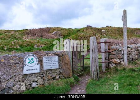 Isle of Anglesey Coast Path signpost and kissing gate next to the 5th century church of St Patrick. Llanbadrig Cemaes Anglesey Wales UK Stock Photo