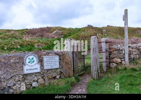 Isle of Anglesey Coast Path signpost and kissing gate next to the 5th century church of St Patrick. Llanbadrig Cemaes Anglesey Wales UK Stock Photo