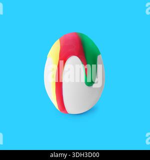 Colorful paint dripping down egg on light blue background. Easter celebration Stock Photo