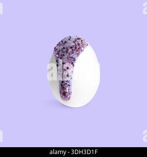 Paint with glitter dripping down egg on lavender background. Easter celebration Stock Photo