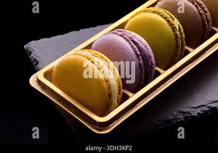 Colorful macarons tasty biscuits on black background. Traditional french dessert, gourmet confectionery pastry Stock Photo