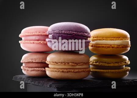 Colorful macarons tasty biscuits on black background. Traditional french dessert, gourmet confectionery pastry Stock Photo