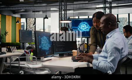 Data scientists doing brainstorming in office, using specialized hardware to accelerate complex AI calculations. IT professionals collaborating, managing deep learning datasets systems, camera A Stock Photo