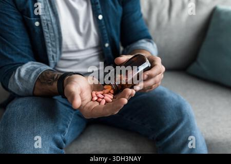 Man pouring capsules from bottle, hold pills on hand. Overdose of medication and pain Stock Photo