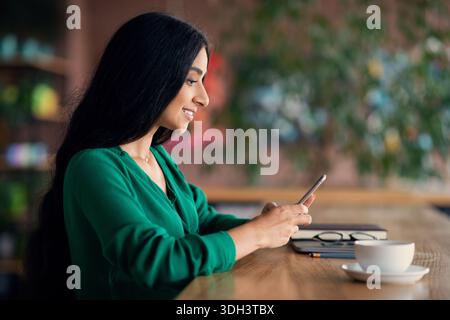 Side view of attractive indian long-haired woman using smartphone Stock Photo