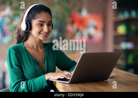 Pretty indian woman attending webinar, cafe interior, copy space Stock Photo