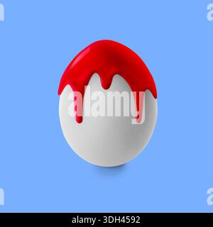 Red paint dripping down egg on pastel blue background. Easter celebration Stock Photo