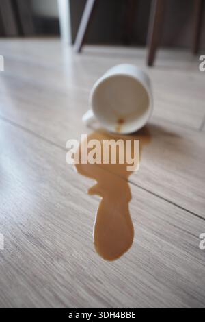 Coffee spills on the floor near a chair in a cafe Stock Photo