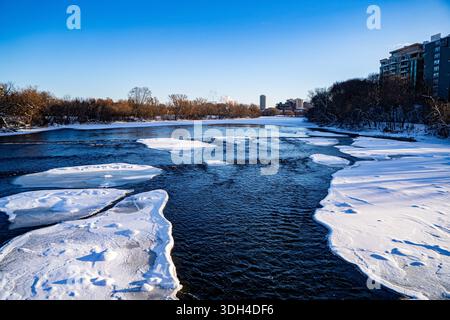 View of partially frozen river flowing through winter landscape. Stock Photo