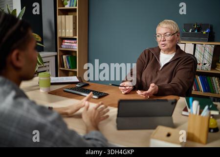 Middle Aged Caucasian Woman Explaining Information to Young Adult Man Stock Photo