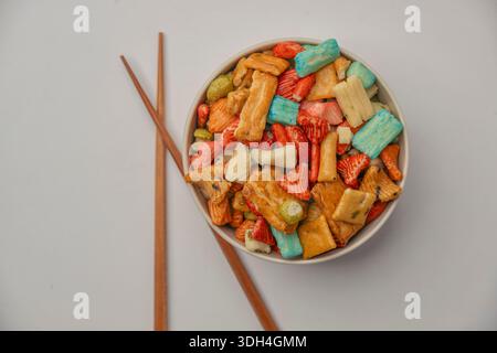 A bowl of colorful snacks with a variety of shapes and sizes. The bowl is filled with a mix of fruits, vegetables, and other snacks. Japanese rice cra Stock Photo
