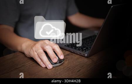 User clicking mouse beside laptop with cloud folder icon. Digital files, file management technology for business, paperless office, document workflow, Stock Photo