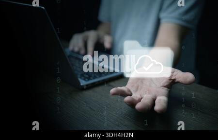 Hand offering cloud folder icon on laptop represents digital files, paperless office, file management, cloud storage technology to enhance document wo Stock Photo