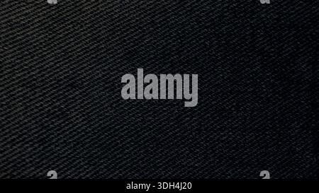 Close-up of high-quality dark blue denim fabric texture. This detailed textile background features classic diagonal twill weave perfect for fashion ap Stock Photo