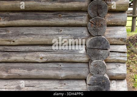 Close up view of a rustic log cabin wall showing stacked horizontal logs and rounded corner logs. Weathered gray wood with visible grain, ideal for ru Stock Photo