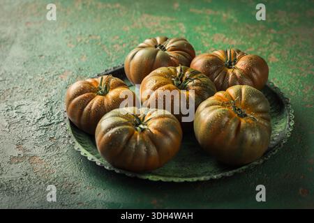 Large black tomato on a green vintage background Stock Photo
