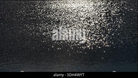 Sunlight sparkling across a rippled lake surface Stock Photo