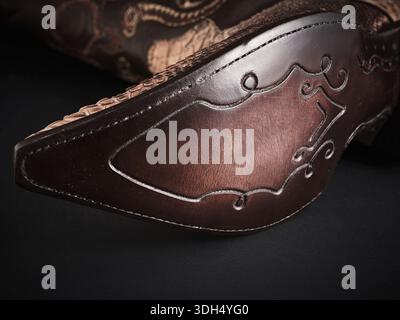 Close-up view of a luxury cowboy boot sole featuring intricate snakeskin texture and a dark embossed leather design, highlighting craftsmanship Stock Photo