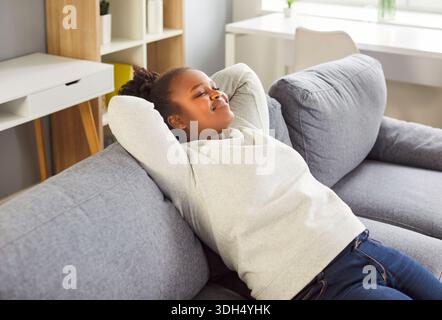Happy African American Woman Resting On The Sofa Enjoying Leisure Time At Home Stock Photo