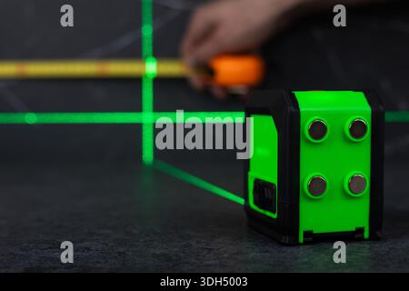 hands of a worker who measures the width of a tabletop with a tape measure and a laser. Stock Photo