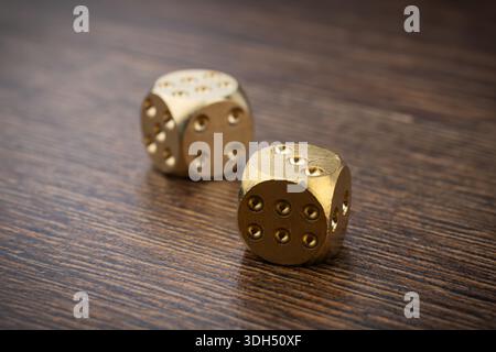 two golden casino dices on wooden table. Stock Photo