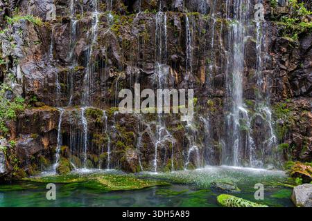 Tranquil waterfall cascading over moss covered rocks in Trialeti, Georgia, during autumn. The clear water flows gently into the emerald pool below, su Stock Photo