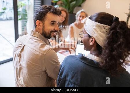 A vibrant team of coworkers engaged in discussion at a modern coworking space. They are collaborating on a project, exchanging ideas, and fostering te Stock Photo