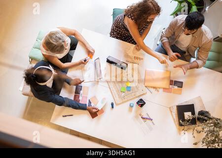 A diverse group of coworkers collaborating around a modern office table, sharing creative ideas and discussing project plans, highlighting teamwork an Stock Photo