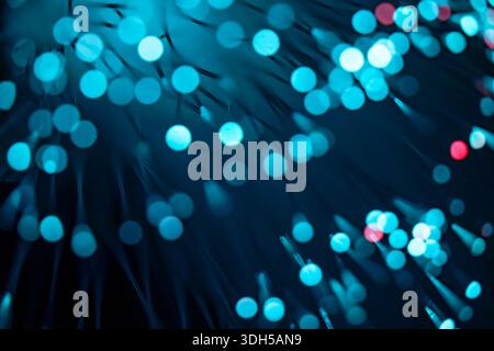 A stunning abstract image featuring blue fiber optic lights with a subtle red hue on a dark background. The bokeh effect creates a sense of depth and Stock Photo
