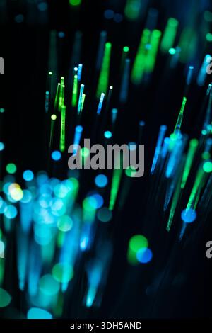A captivating close-up of fiber optic strands glowing in green and blue hues. The background features an abstract bokeh effect, enhancing the vibrant Stock Photo