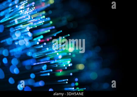 Close-up of fiber optic cables emitting vibrant blue and green light with a captivating bokeh effect. The abstract background sets a futuristic and di Stock Photo