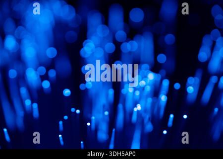 A mesmerizing array of blue fiber optic lights creates an abstract bokeh effect against a dark background, showcasing a vibrant display of technology Stock Photo