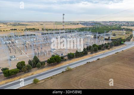 Aerial view of a large power station set amidst rural fields and distant residential areas. The image showcases an expansive electrical substation wit Stock Photo