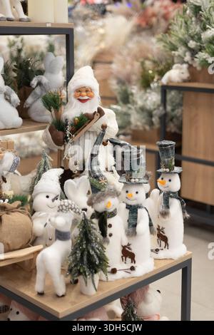 A vibrant Christmas toy store display features plush snowmen with patterned hats and scarves, a cheerful Santa figurine, and decorative trees on woode Stock Photo