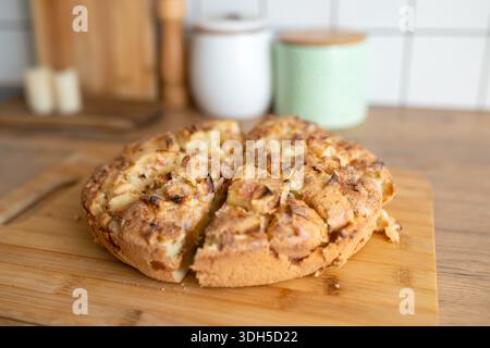 A close-up of a freshly baked homemade apple pie on a wooden cutting board, showcasing its golden crust and delicious apple chunks, perfect for a cozy Stock Photo