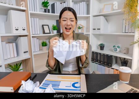Stressed businesswoman dealing with heavy work pressure, reacting emotionally while reviewing reports and facing tight deadlines, highlighting workpla Stock Photo