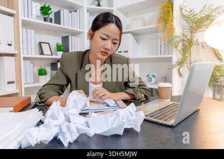 Stressed businesswoman dealing with heavy work pressure, reacting emotionally while reviewing reports and facing tight deadlines, highlighting workpla Stock Photo