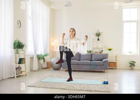 Senior Woman Doing Stretching Exercises at Home for Fitness and Health Stock Photo