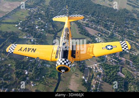 The North American SNJ-6 Texan, Harvard, registration N3639F, serial 121-42981, is a U.S. Navy single-seat, single-engine trainer aircraft with Pratt & Whitney R-1340 Wasp radial engine, low-wing design, and tailwheel landing gear. Captured in air-to-air formation flight at Sun N Fun Aerospace Expo 2025, Florida, highlighting classic military trainer characteristics, maneuverability, and pilot training capabilities. Stock Photo