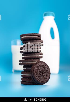 Horishni PlavniUkraine-August 21th,2022: OREO cookies in stack with glass of fresh milk on blue background (American famous cookie brand) Stock Photo