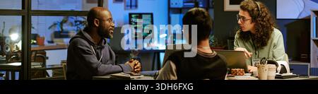Multiethnic Young Adults Collaborating during Nighttime Office Meeting Stock Photo