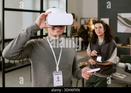 Young Caucasian Man Using Virtual Reality Headset While Smiling Indoors Stock Photo