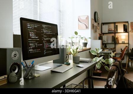 Modern Home Office Desk Featuring Computer Monitor Displaying Programming Code Stock Photo