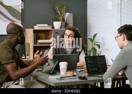 Multiethnic Young Adults Collaborating during Office Meeting with Laptops Stock Photo