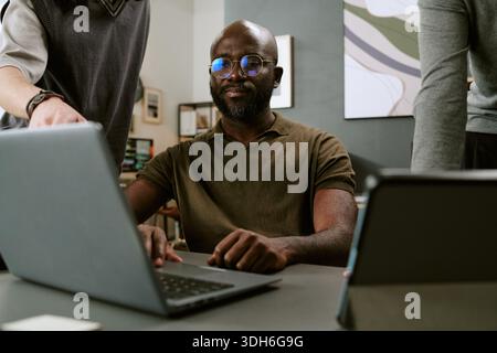Young Black Man Collaborating with Colleagues in Modern Office Stock Photo