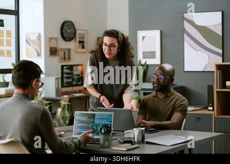 Young Caucasian Man Explaining Project to Diverse Colleagues in Office Stock Photo