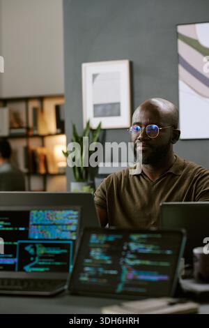 Young Black Man Focusing on Software Development in Contemporary Office Stock Photo