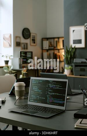 Modern Office Workspace Featuring Laptop Displaying Programming Code Stock Photo