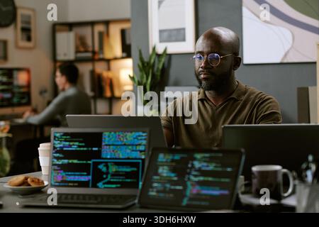 Young Black Man Working on Computer Programming in Modern Office Stock Photo